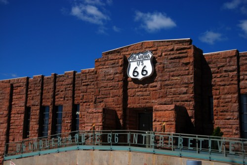 Historic building with a Route 66 sign, featuring a stone facade and blue sky in the background.