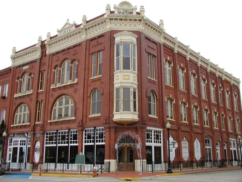 Historic red brick building with ornate architectural details and large windows, located on a street corner.