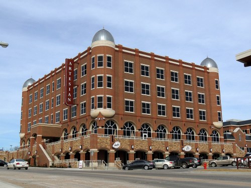 A large brick building with rounded domes, featuring arched windows and a sign that reads "Artesian."
