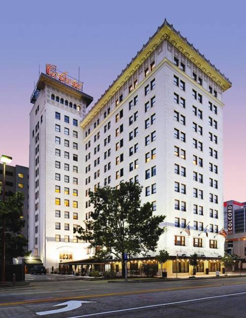 Historic white building with a tall tower, illuminated windows, and a vintage sign, set against a twilight sky.