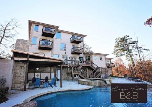 A multi-story bed and breakfast with balconies, surrounded by trees and featuring a pool in the foreground.