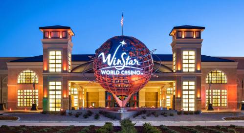 Exterior of WinStar World Casino at dusk, featuring a large illuminated globe sign and modern architecture.
