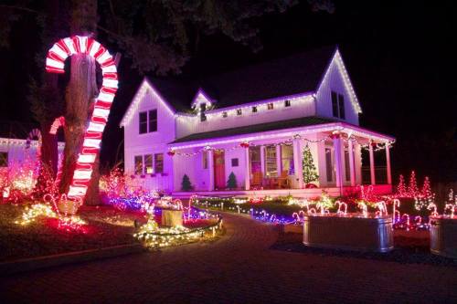A beautifully decorated house for Christmas, featuring colorful lights, candy canes, and a festive atmosphere at night.