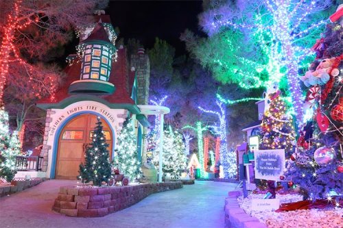 A festive scene with colorful lights, decorated trees, and a charming building, creating a magical holiday atmosphere.