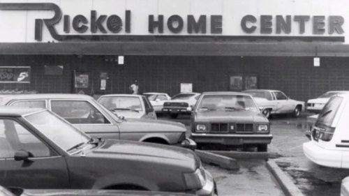 Black and white photo of Rickel Home Center storefront with parked cars in the foreground.