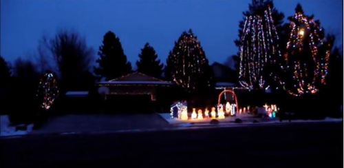 A house decorated with colorful Christmas lights and festive displays, set against a twilight sky.