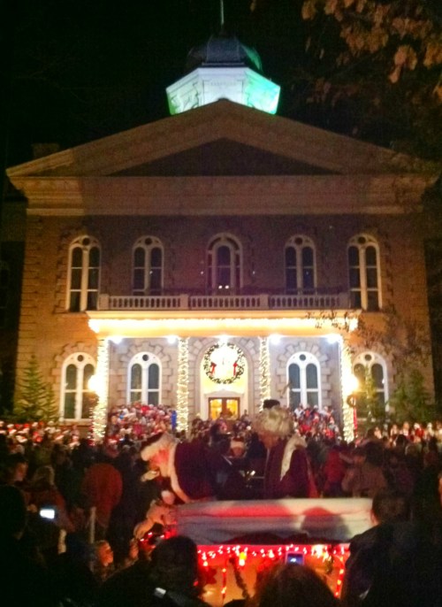 A festive night scene with a crowd gathered in front of a decorated building, celebrating a holiday event.