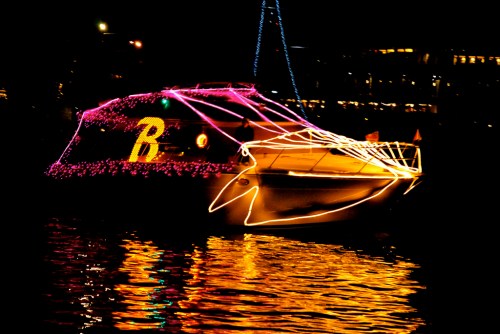 A brightly lit boat decorated with colorful lights, reflecting on the water at night.