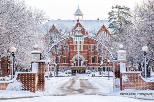 Historic building framed by a snow-covered archway, surrounded by trees and a winter landscape.