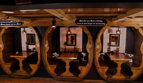 Three wooden booths with tables in a cozy restaurant setting, featuring decorative elements and warm lighting.
