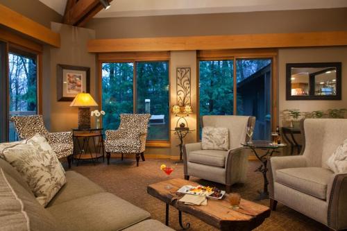 Cozy living room with large windows, comfortable seating, and a wooden coffee table, surrounded by greenery.