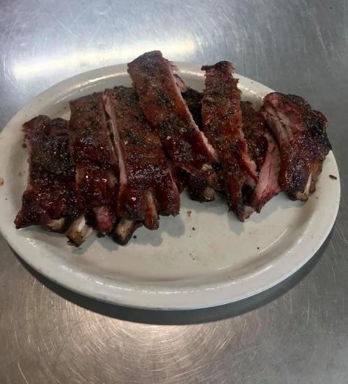 A plate of sliced, smoky barbecue ribs with a dark, caramelized glaze.