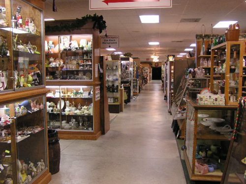 A wide aisle in an antique shop lined with display cases filled with various collectibles and decorative items.