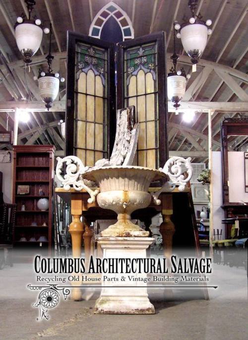 A vintage architectural salvage shop featuring a decorative fountain and stained glass windows in a rustic setting.