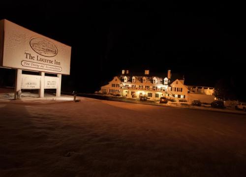 A warmly lit inn at night, surrounded by snow, with a large sign in front displaying its name.