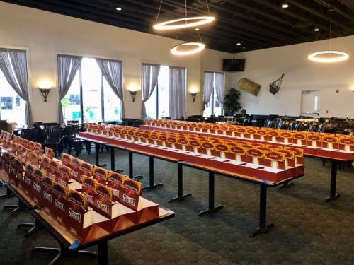 A spacious room with rows of tables displaying colorful boxes, likely for an event or gathering.