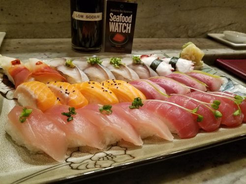 A colorful assortment of sushi on a decorative plate, featuring various types of fish and garnishes.