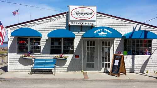 A diner with blue awnings and a sign reading "Waco Diner" and "Narragansett Lager Beer" in a sunny outdoor setting.