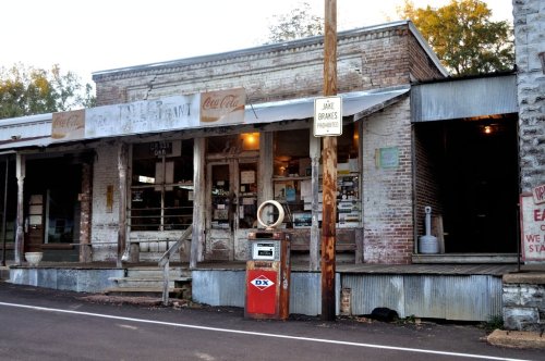 A vintage restaurant with a weathered facade, featuring a classic gas pump and rustic signage on a quiet street.