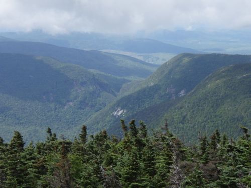 A panoramic view of lush green mountains and valleys under a cloudy sky.