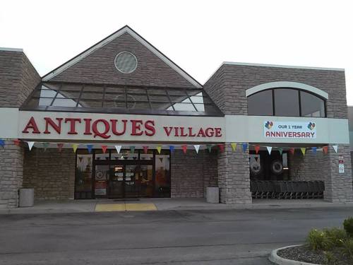 Exterior of Antiques Village with a banner celebrating its anniversary and colorful flags adorning the entrance.