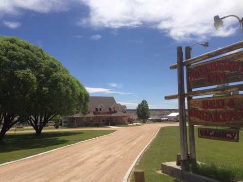 A gravel road leads to the Blueberry Inn, featuring a sign for bed and breakfast with a clear blue sky above.