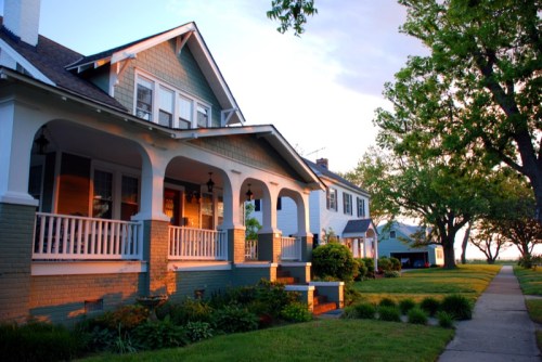 A row of charming houses with porches, surrounded by greenery, bathed in warm evening light.