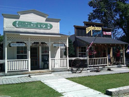 Two vintage-style storefronts: a barbershop on the left and a general store on the right, with a wooden walkway in front.