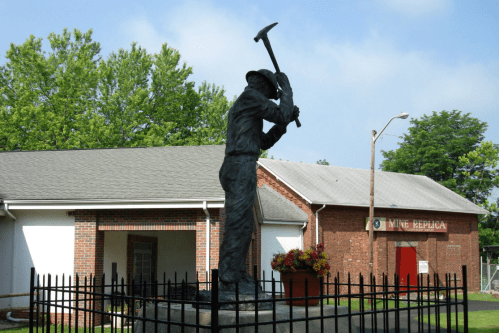 A miner statue holding a pickaxe stands in front of a brick building with a sign reading "Mine Republic."