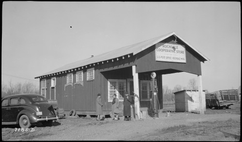A vintage cooperative store with a post office sign, featuring four people and an old car parked outside.