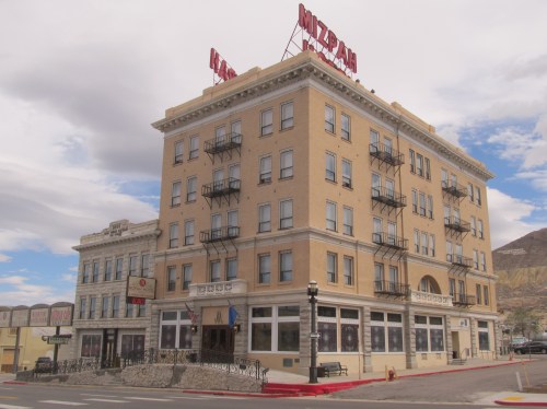 Historic Mizpah Hotel building with balconies, red signage, and a cloudy sky in the background.