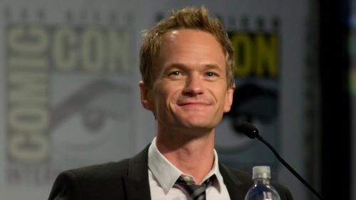 Neil Patrick Harris in front of a microphone, wearing a suit