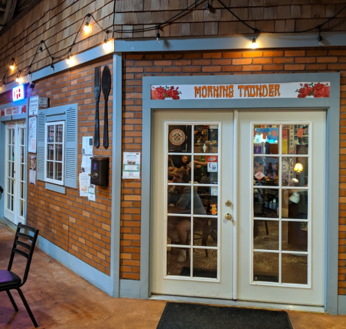 Exterior view of a restaurant entrance with a brick facade and large glass doors, labeled "Morning Thunder."
