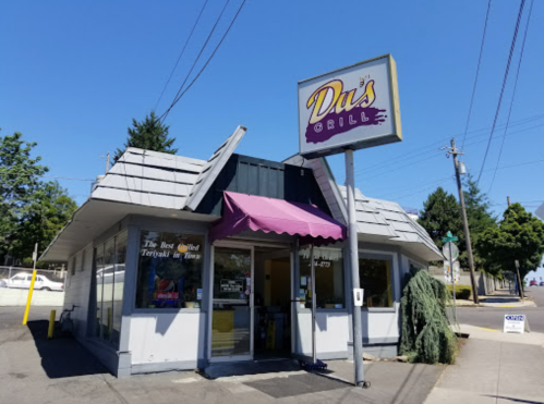 A small restaurant with a gray roof and purple awning, featuring a sign that reads "D's Grill" on a sunny day.