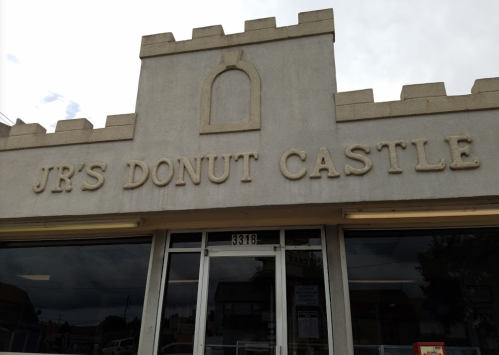 Sign for "JR's Donut Castle" on a building with a castle-like design.