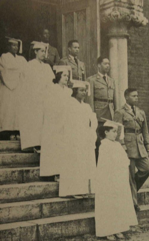 A historical black-and-white photo of a group of nurses and military personnel standing on steps.