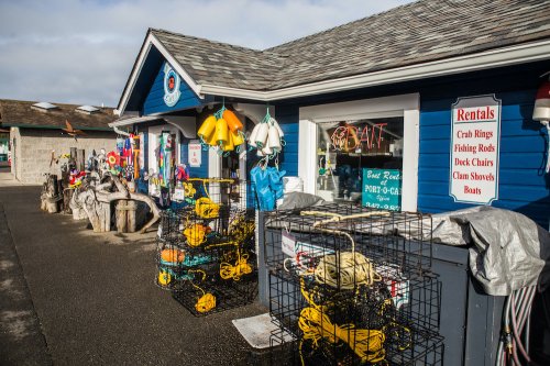 Colorful fishing gear and rental equipment displayed outside a blue building, with signs for crab rings and boats.