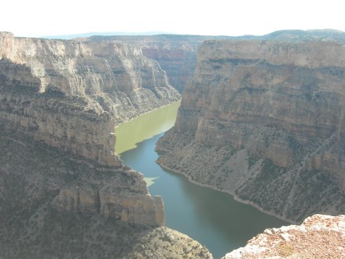 A scenic view of a winding river surrounded by steep, rocky cliffs under a clear sky.