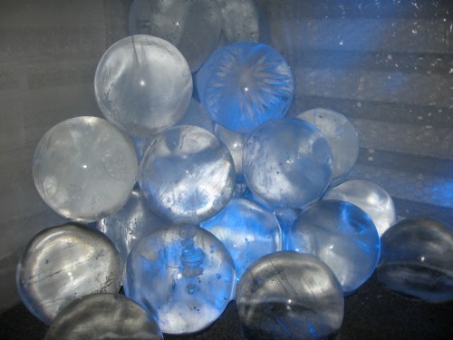 A cluster of translucent, spherical ice sculptures illuminated by blue light, creating a cool, ethereal atmosphere.