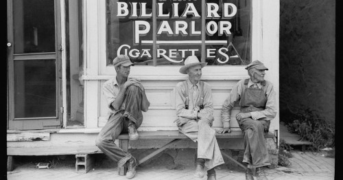 Three men sitting outside a billiard parlor, wearing hats and work clothes, with a sign for "Cigarettes" in the background.