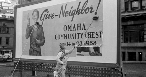 A worker paints a large billboard promoting the Omaha Community Chest in 1938.