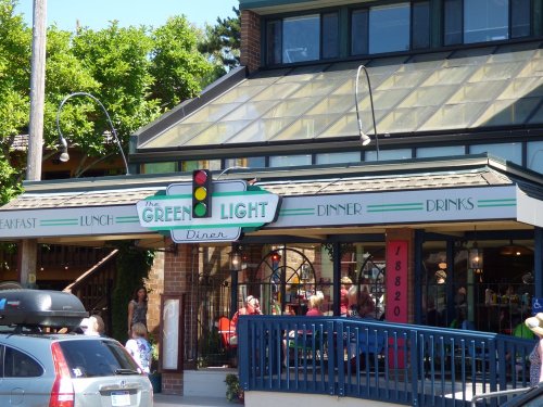 Exterior of The Green Light Diner, featuring a colorful sign and a traffic light, with outdoor seating visible.