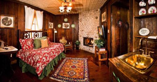 Cozy rustic bedroom with a floral bedspread, stone fireplace, wooden walls, and decorative plates.