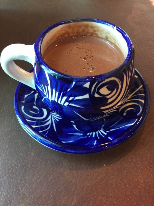 A blue and white patterned cup filled with hot chocolate, resting on a matching saucer.