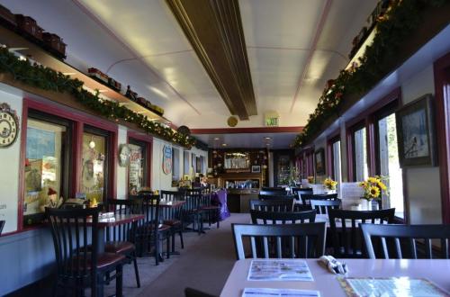 Interior of a cozy restaurant with black chairs, festive decorations, and a warm, inviting atmosphere.
