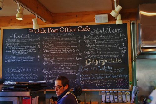 A chalkboard menu at The Olde Post Office Cafe featuring sandwiches, salads, and daily specials.
