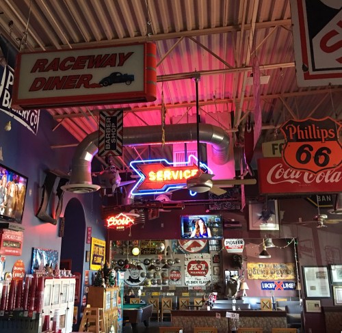 A vibrant diner interior featuring neon signs, vintage decor, and memorabilia, creating a nostalgic atmosphere.