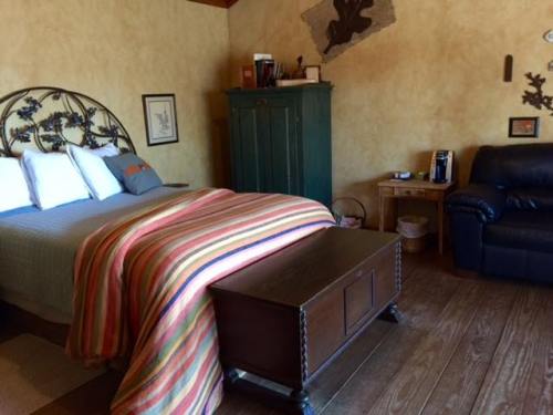 Cozy bedroom featuring a striped blanket, wooden furniture, and a leather chair in warm, inviting tones.