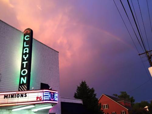 A theater marquee reading "CLAYTON" with "MINIONS" below, set against a colorful sky with a faint rainbow.