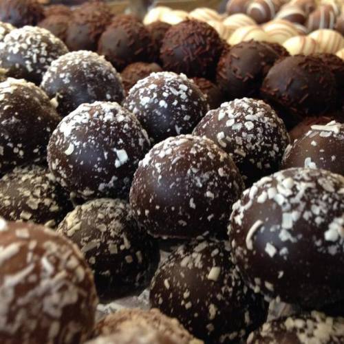 A close-up of assorted chocolate truffles, featuring dark chocolate and white chocolate-coated varieties.
